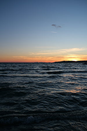 Sunset over a calm ocean with distant land., Sea and Land, HD phone wallpaper