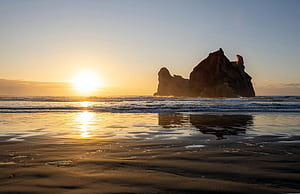 Sunset over a rocky ocean coastline with reflection, Wharariki Beach, HD wallpaper